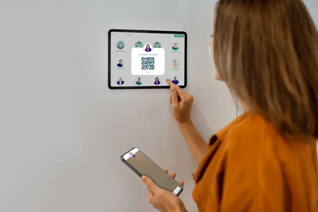 Vrouw scant met haar telefoon een QR-code op een tablet aan de muur